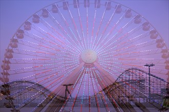 Double exposure of ferris wheel and roller coaster