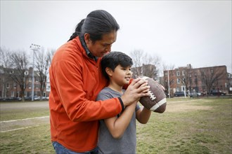 Native American father teaching son to throw football