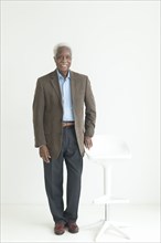 Portrait of older Black man leaning on store