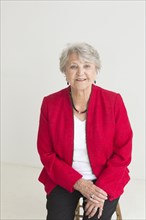 Portrait of older Caucasian woman sitting on stool
