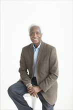Portrait of older smiling Black man sitting on stool