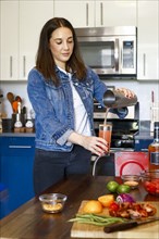 Woman pouring cocktail in kitchen