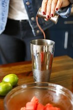 Woman pouring liquid into cocktail shaker