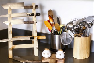 Knives in rack near kitchen utensils
