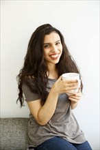 Mixed race woman on sofa drinking coffee