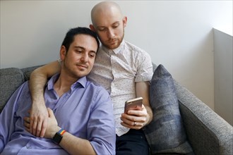 Caucasian men holding hands and texting on cell phone