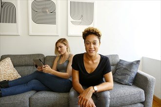Women sitting on sofa using digital tablet