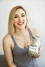 Caucasian woman showing jar of money for college