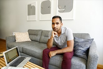 Mixed race man relaxing on sofa near laptop