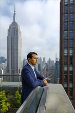 Pensive Caucasian businessman leaning on urban rooftop