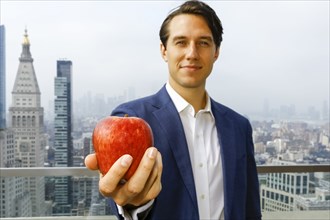 Caucasian businessman showing apple on urban rooftop
