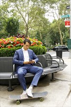 Caucasian businessman on park bench texting on cell phone