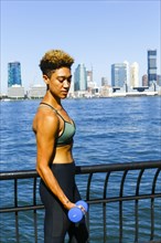 Mixed race woman lifting dumbbells at waterfront