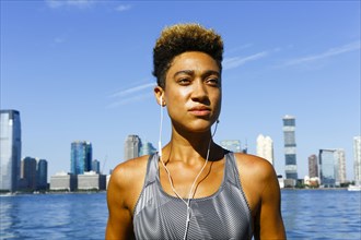 Mixed race woman at waterfront listening to earbuds
