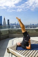 Caucasian man with legs raised performing yoga on urban rooftop