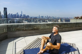Caucasian man meditating on urban rooftop