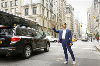 Caucasian businessman standing in street hailing taxi