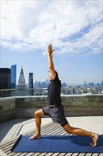 Caucasian man practicing yoga on urban rooftop