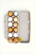 Colored eggs and one broken egg in carton