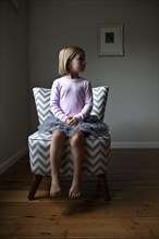 Mixed race girl sitting on chair