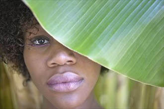 Close up portrait of woman behind banana leaf
