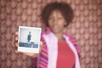 Blurred image of woman holding up old photograph