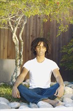 Teenage boy meditating outdoors