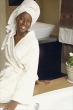 African American woman in hotel bathroom wearing bathrobe