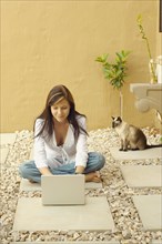 Woman with laptop and cat outdoors