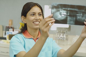 Indian female dental assistant looking at x-rays