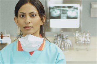 Indian female dental assistant next to x-rays