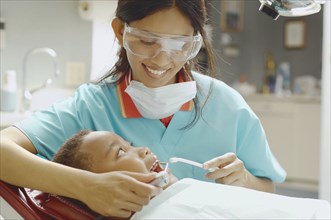 Indian female dental assistant working on African boy