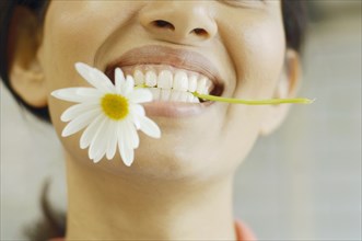 Woman smiling with flower in her teeth