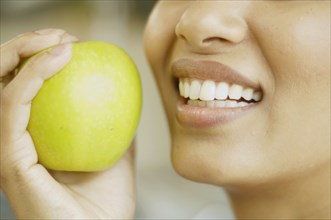 Close up of woman holding apple next to her mouth