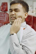 Indian man in dentist's chair with jaw pain