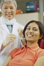 Senior Asian female dentist next to Indian female patient