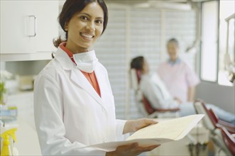 Indian female dentist holding chart and smiling