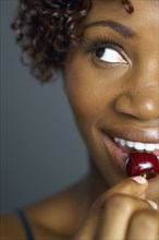 Close up of African woman eating cherry
