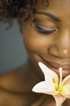 Close up of African woman smelling flower