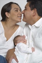 Hispanic parents hugging with baby