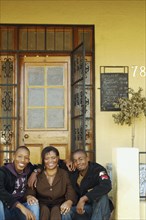 African mother and adult sons on porch steps