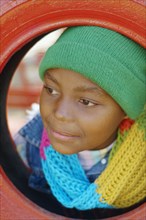 African girl leaning head through tire swing