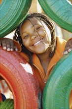 African girl looking through tire play structure