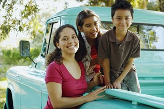 Hispanic mother and children in back of truck