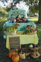 Multi-ethnic family in truck at farm stand