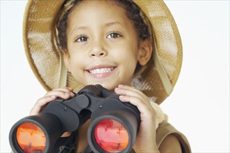 Mixed race boy in safari hat holding binoculars