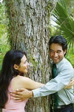 Hispanic couple hugging tree