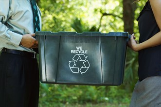 Hispanic business people carrying recycling bin