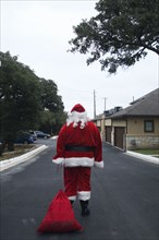 Santa dragging sack down road