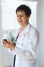 Caucasian doctor using cell phone in office